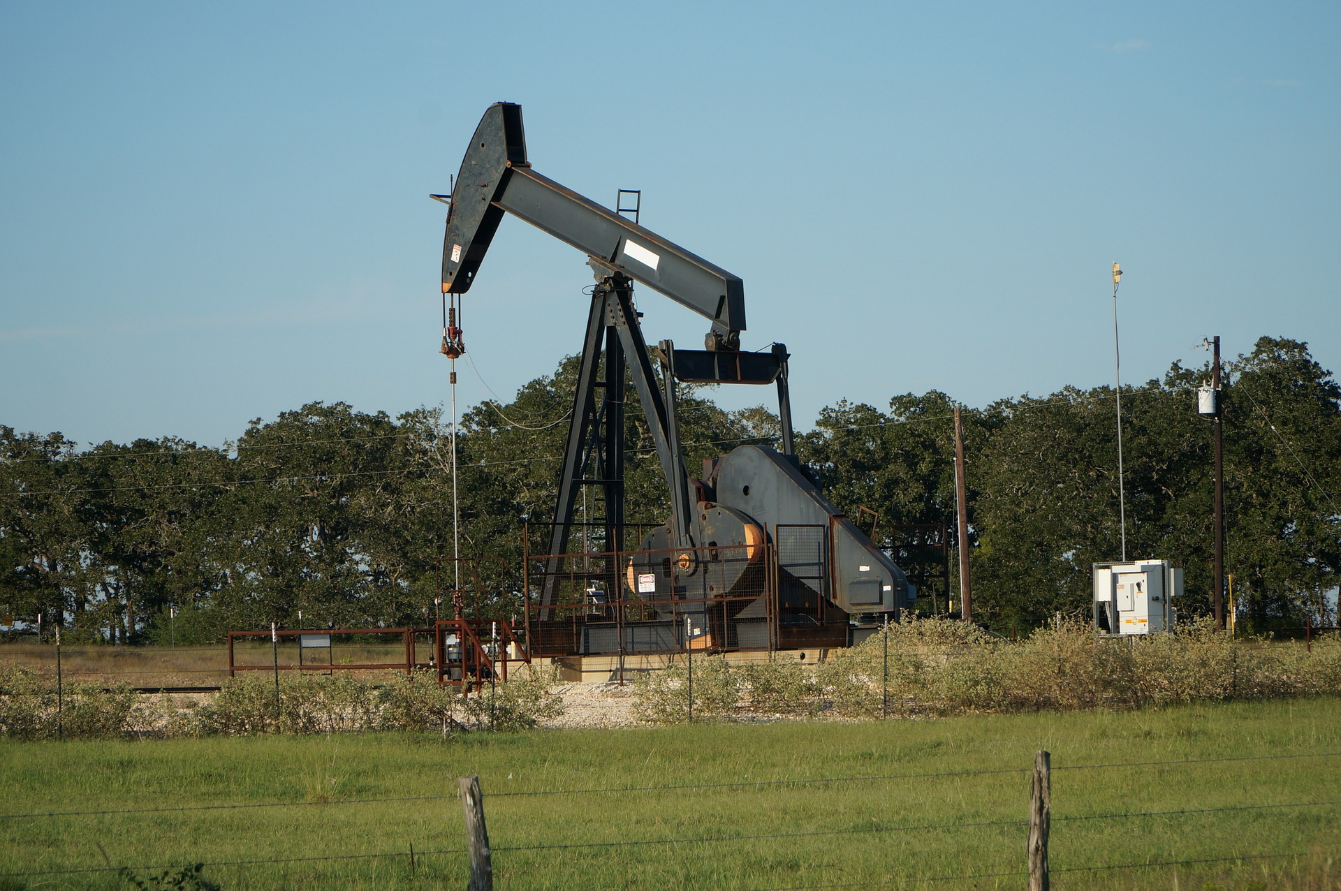 An oil well brough to life in a field of green.