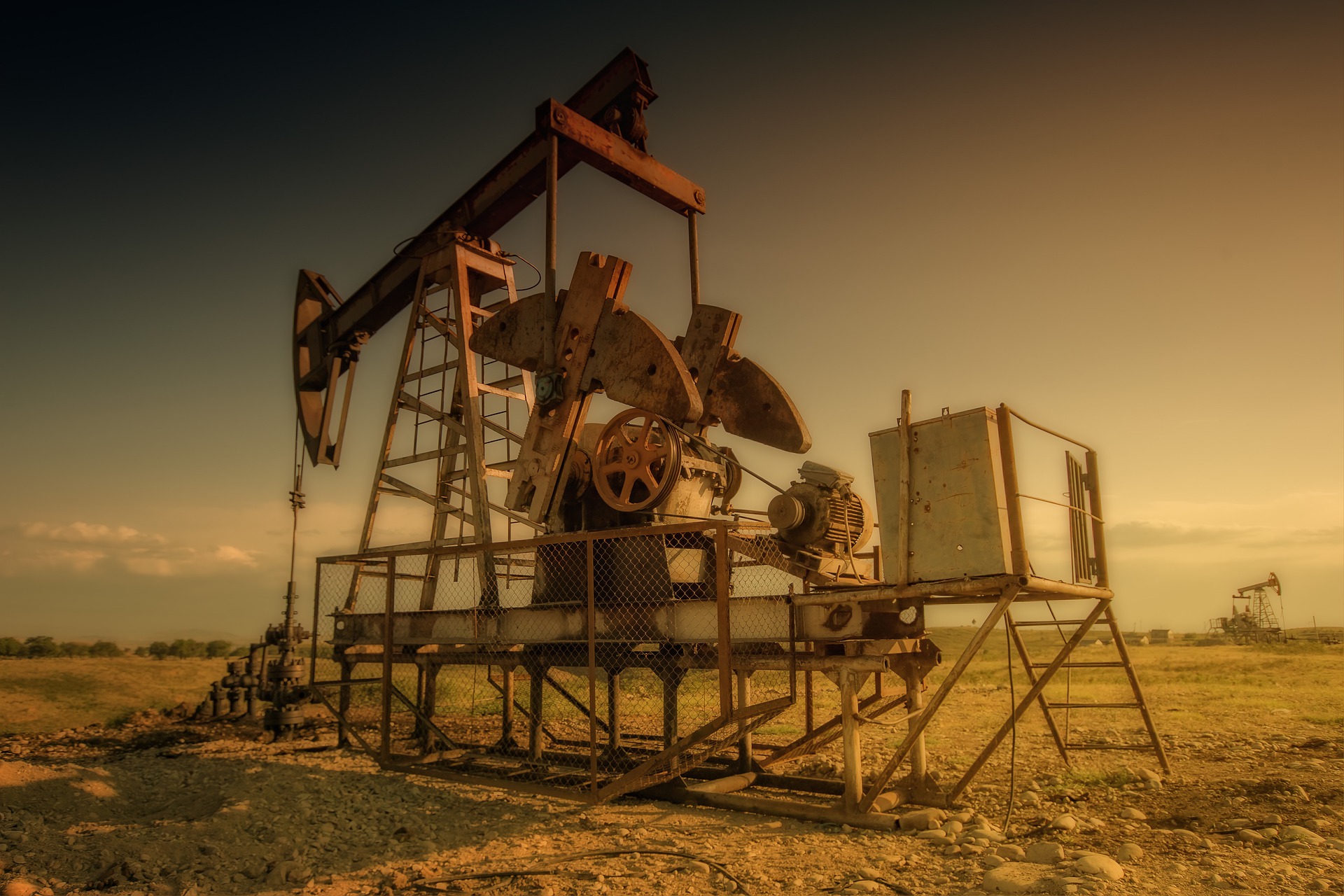 Golden sunset light hitting a pump jack attached to an orphaned well.